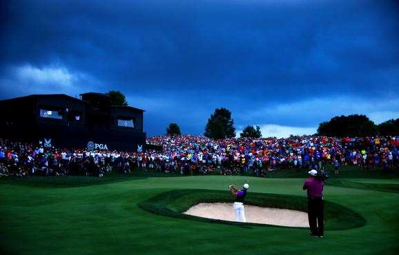 Rory McIlroy hits a shot from a greenside bunker on the 18th hole as darkness falls across the course. PHOTO: Getty Images