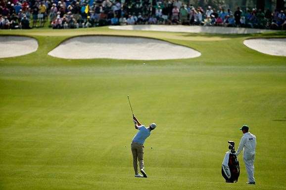Adam Scott hits an approach shot as caddie Mike Kerr looks on during his practice round Monday. PHOTO: Getty Images