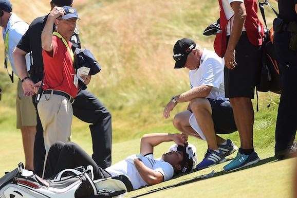 Jason Day is tended to by caddie Colin Swatton as he lays on the 9th fairway. (Photo by Harry How/Getty Images)