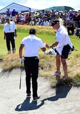 Day is tended to by caddie Colin Swatton after playing a bunker shot, moments after regaining his feet from a collapse. (Photo by Harry How/Getty Images)