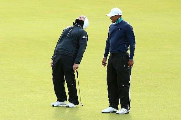 Louis Oosthuizen and Tiger Woods laugh as Oosthuizen's ball moves due to high winds on the 13th green before play is suspended. Photo by Andrew Redington/Getty Images.