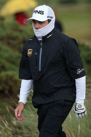 Louis Oosthuizen attempts to keep warm during the late stages of the second round. PHOTO: Andrew Redington/Getty Images.