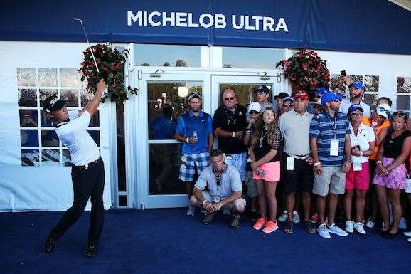 Matt Jones plays his second shot from the carpet of a hospitality tent on the 9th hole. PHOTO: Andrew Redington/Getty Images.