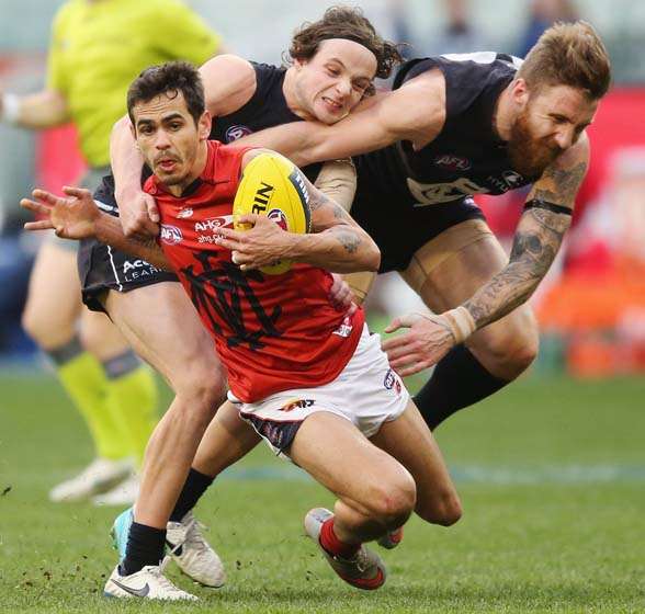 MELBOURNE, AUSTRALIA - AUGUST 23: Jeff Garlett of the Demons is tackled by Dylan Buckley and Zach Tuohy (R) of the Blues during the round 21 AFL match between the Carlton Blues and the Melbourne Demons at Melbourne Cricket Ground on August 23, 2015 in Melbourne, Australia. (Photo by Michael Dodge/Getty Images)