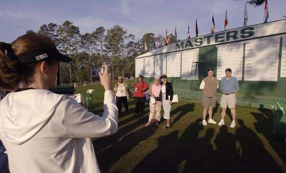 Taking photos in front of the huge leaderboard near the 1st tee is a tradition for Masters patrons. PHOTO: Roberto Schmidt /AFP/Getty Images