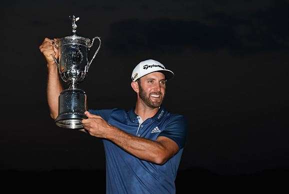 Dustin Johnson hoists the US Open trophy high. PHOTO: Ross Kinnaird/Getty Images.