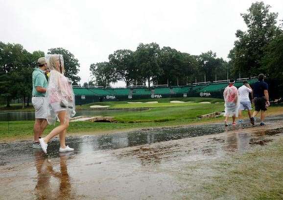 Fans walk on the 18th hole during the extended rain delay. PHOTO: Andy Lyons/Getty Images.