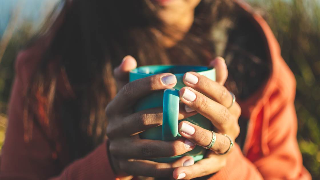 A woman with beautiful hands and healthy nails cradling a mug of hot tea. A woman with beautiful hands and healthy nails cradling a mug of hot tea.