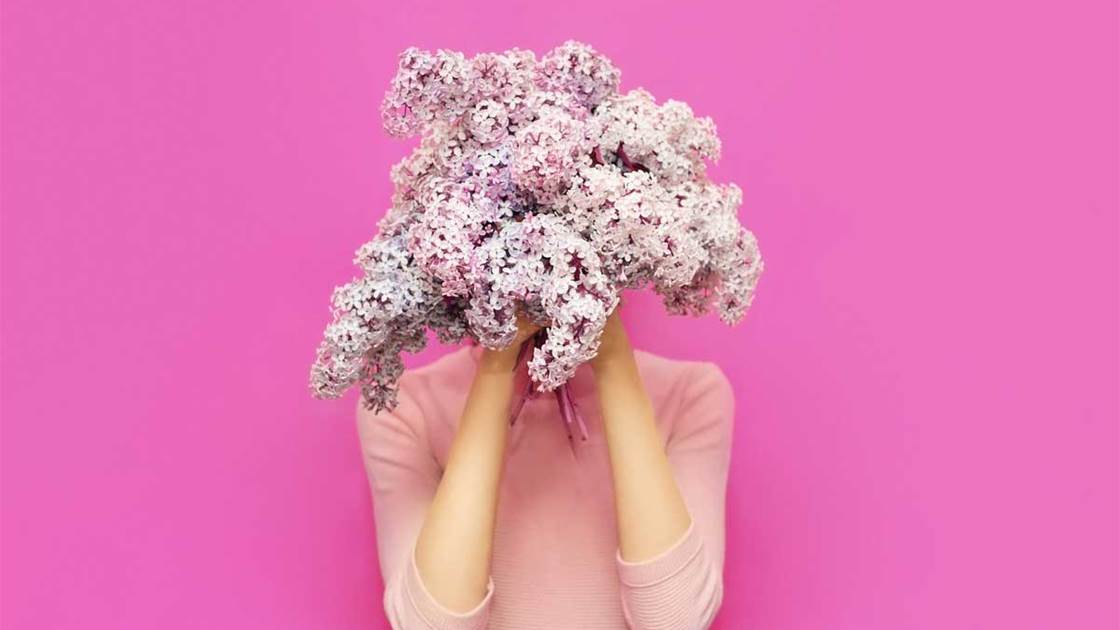 Woman hiding behind a bunch of wild flowers, signifying spring allergies or hayfever. Woman hiding behind a bunch of wild flowers, signifying spring allergies or hayfever.