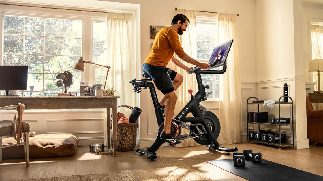 A man trialling a Peloton Bike at home. A man trialling a Peloton Bike at home.