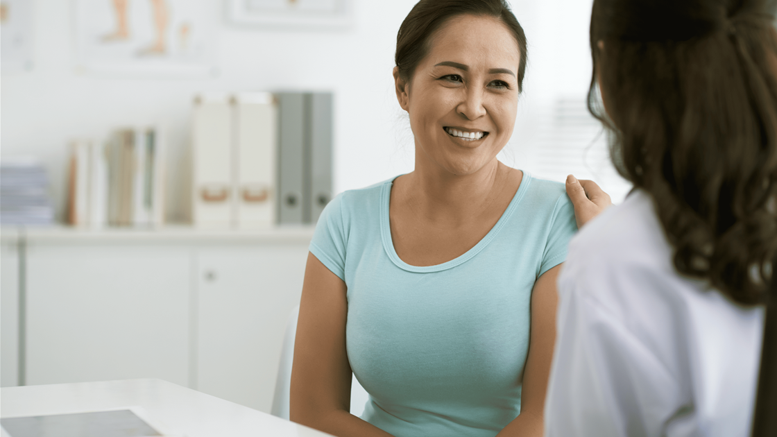 Woman smiling during post-treatment breast cancer check-up with her doctor Woman smiling during post-treatment breast cancer check-up with her doctor