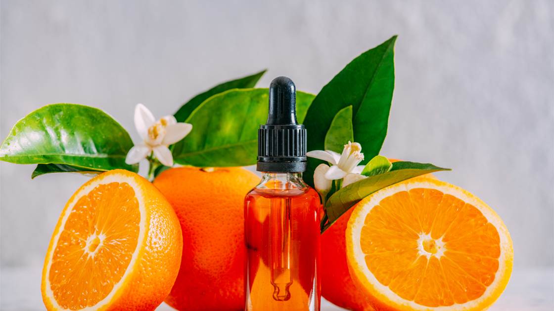 Glass dropper bottle of vitamin C serum with fresh oranges Glass dropper bottle of vitamin C serum with fresh oranges