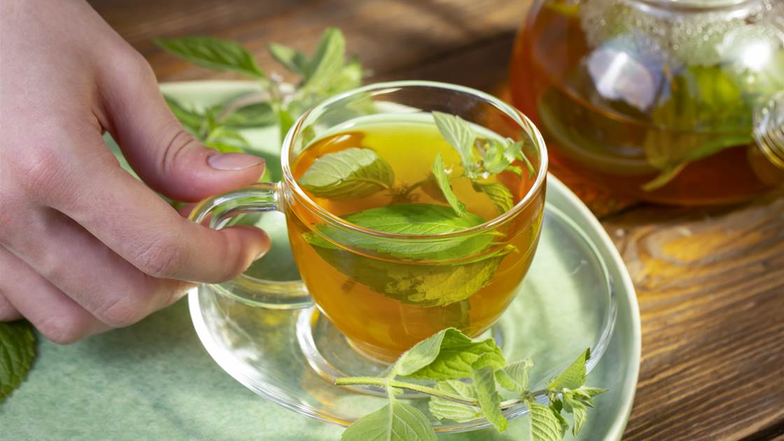 Glass cup of herbal tea with fresh mint on a saucer, for a guide to the best teas for digestion and how to use them Glass cup of herbal tea with fresh mint on a saucer, for a guide to the best teas for digestion and how to use them