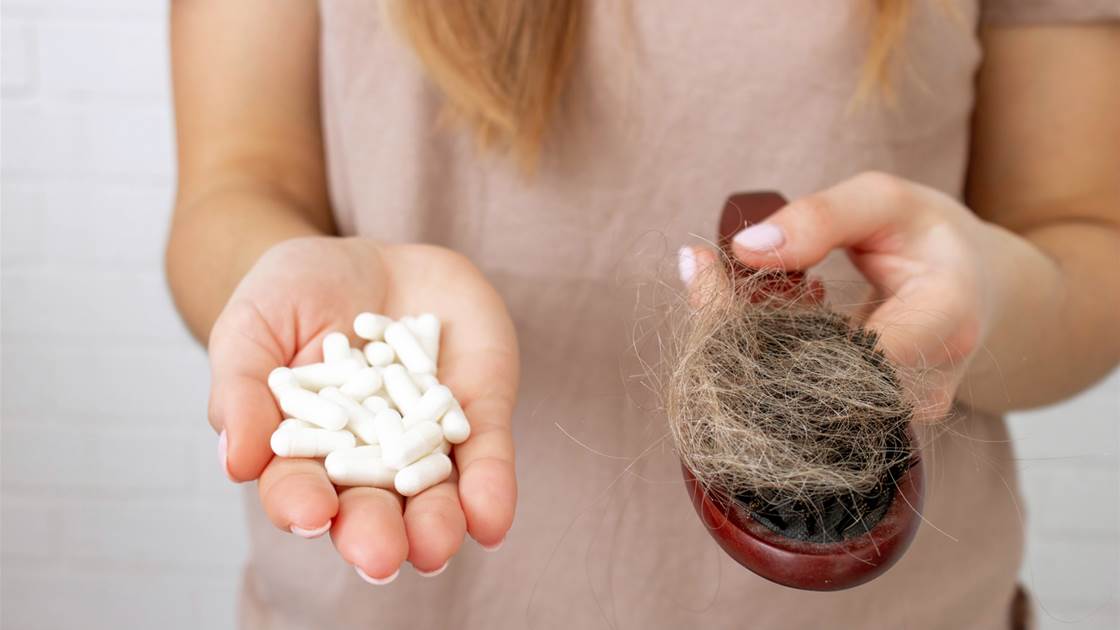Hands holding white supplement capsules and a hairbrush full of shed hair, illustrating hair thinning and treatment choices. Hands holding white supplement capsules and a hairbrush full of shed hair, illustrating hair thinning and treatment choices.