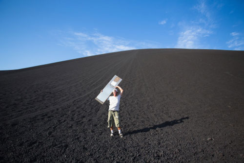 A volcano-boarding holds his board over his head! Photo: Getty Images
